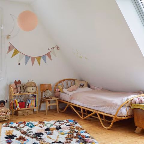 Kinderzimmer mit Dachschräge und Bett aus Rattan