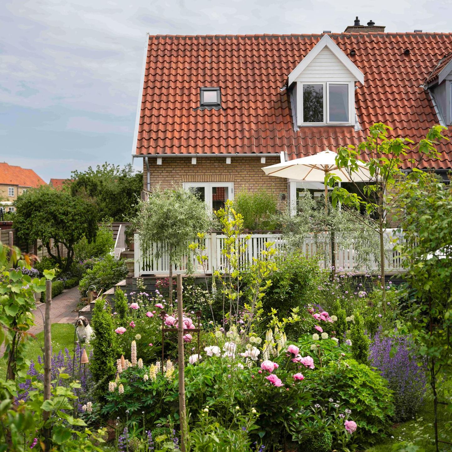 Reihenhaus mit Garten voller bunter Sträucher und Blumen