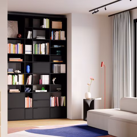 Wohnzimmer mit Sofa, schwarzem Einbauschrank und Deko